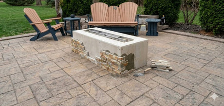 Rectangular fire pit foundation kit being assembled with stone veneer tiles on paver patio with Adirondack chairs in background Rectangular fire pit foundation kit being assembled with stone veneer tiles on paver patio with Adirondack chairs in background
