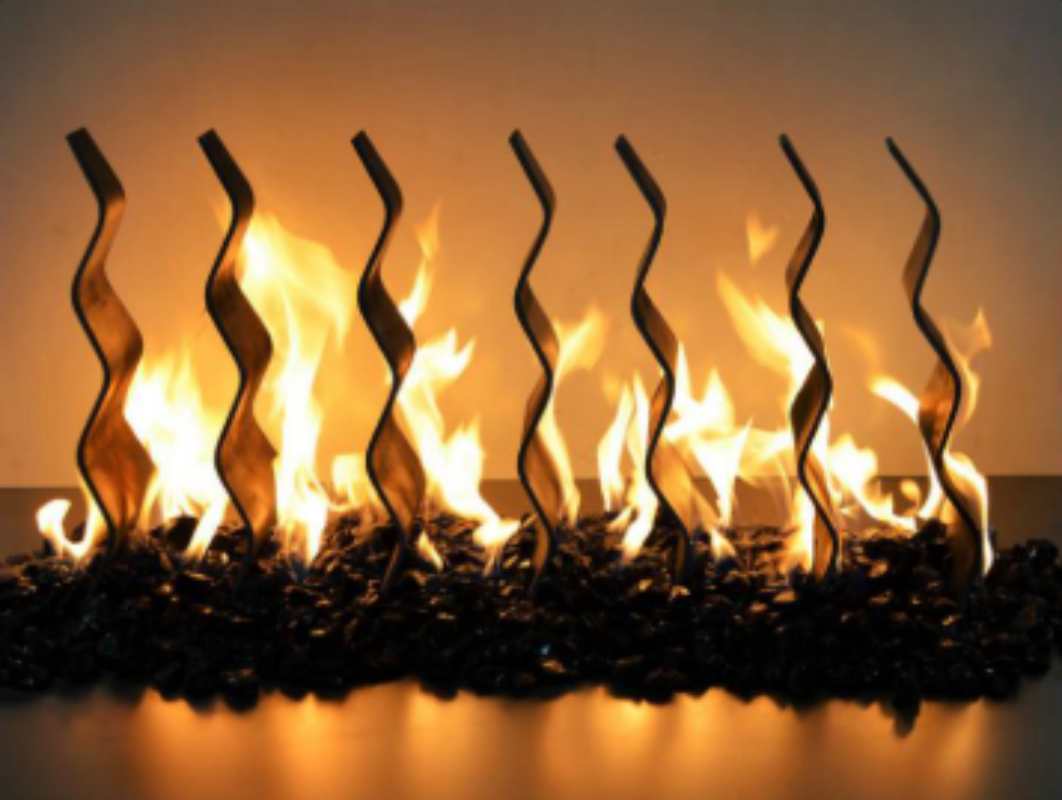 Artificial fireplace insert with wavy metal flames on a dark background