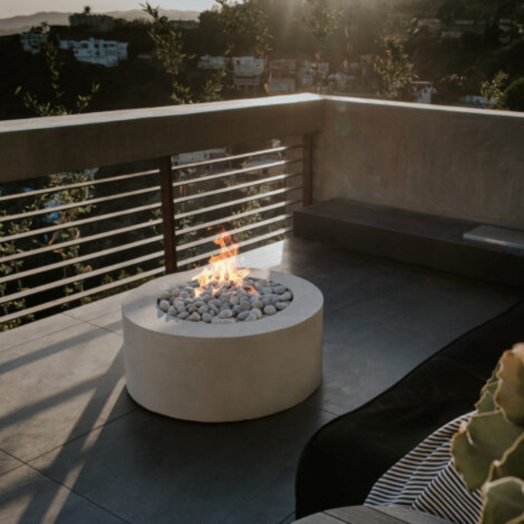 Fire pit on a balcony with a scenic view of buildings and trees.