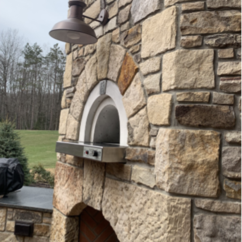 Outdoor stone fireplace with pizza oven against a natural background