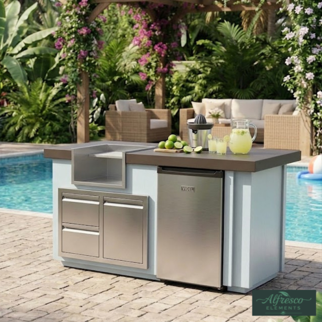 Outdoor kitchen island with sink and refrigerator by a pool, surrounded by greenery.