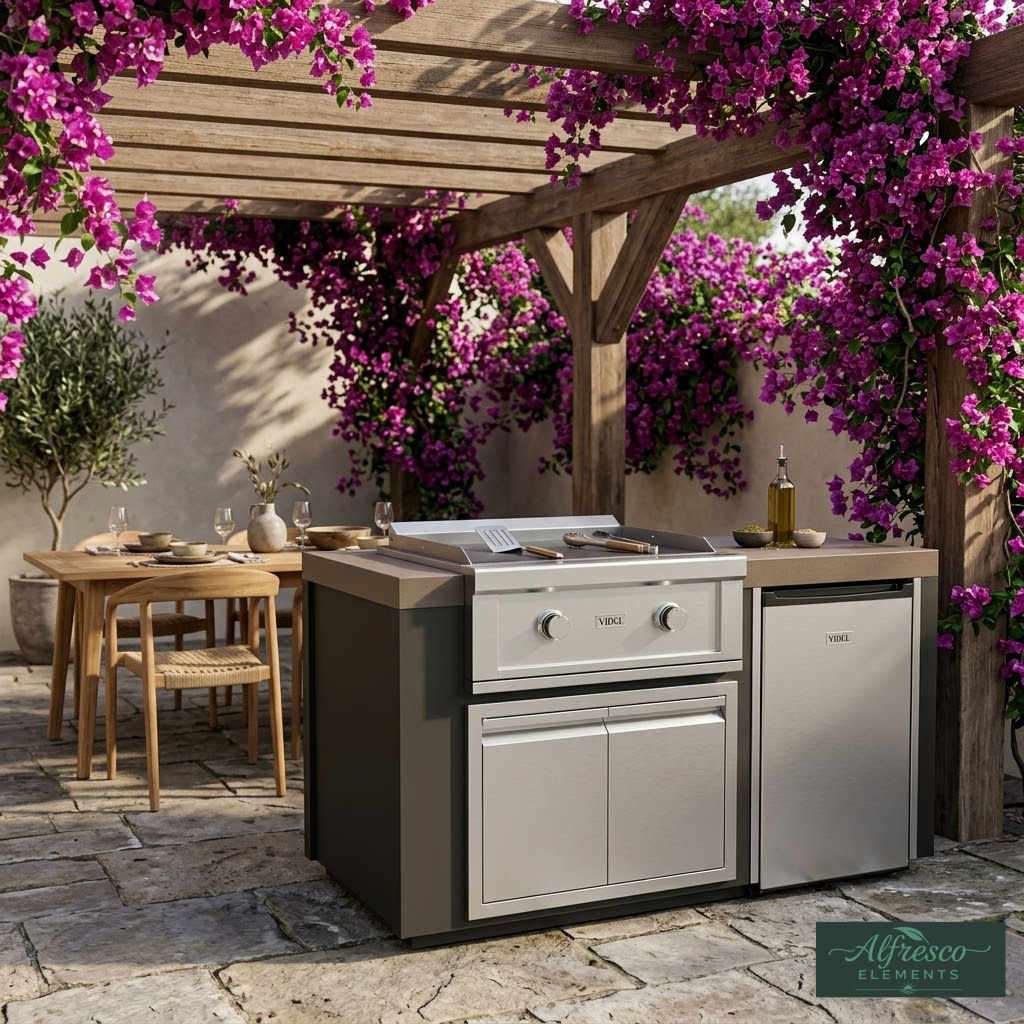 Outdoor kitchen with grill and refrigerator under a wooden pergola with purple flowers.
