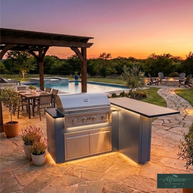 Outdoor kitchen with grill and bar area by a pool at sunset